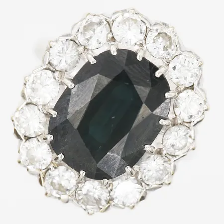 Carmoséring med safir samt diamanter 14 x ca 0,16ct, varierad slipning samt kvalitet TC-C(I-J)Si-P, safir 13,5x10mm, stl: 17½, bredd: 3-22mm, en diamant med skada på rondist, bruksslitage, ej stämplad, 18K vitguld.  Vikt: 8,9 g
