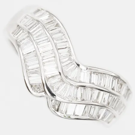Ring med baguetteslipade diamanter totalt 1,10ctv enligt gravyr, tre troligtvis syntetiska, stl: 16½, bredd: 3-8mm, nyskick, 18K vitguld.  Vikt: 6,4 g