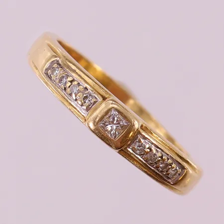 Ring med prinsesslipad diamant 1 x ca 0,05ct, briljantslipade 8 x 0,01ct, stl: 19, bredd 3-4mm, bucklig, 18K.  Vikt: 4,6 g