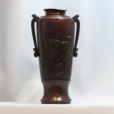 Vas i brons, Japan Meiji-perioden (1868-1912). Signerad i botten, reliefdekor av blommor och fjärilar samt fågel, höjd 26,5cm, mynningen har en buckla (skev) med hänklar  Skickas med postpaket.