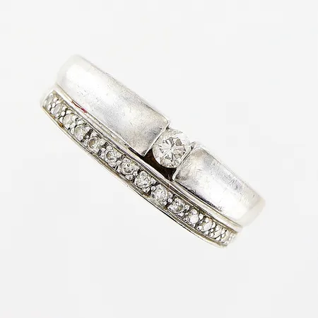 Ring stl 18¾, bredd 4,5-7mm, diamanter 1 x ca 0,15ct, briljantslipad, 15 x ca 0,01ct, briljantslipade, GHA, vitguld, behov av rodiering, 18K Vikt: 7,6 g
