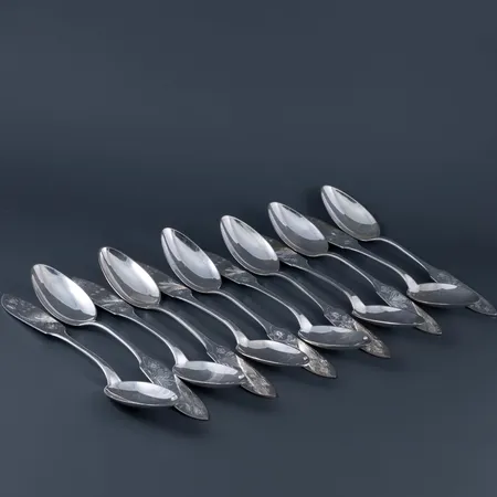 Tolv bordsskedar Tornedal/Finnmyrten i silver (830/1000). Längd 175 mm. Besticklinda medföljer. Vikt: 395,5g. Tillverkade mellan 1952  1961 av C O Persson, Haparanda. 2 skedar med personlig gravyr.