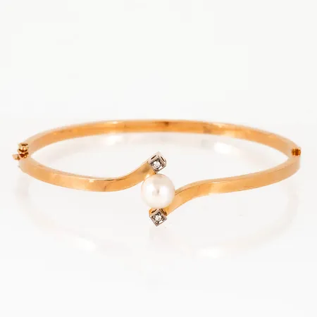 Armring i 18K guld, med en odlad saltvattenspärla Ø 7,3 mm och 2 x ca 0,015ct åttkantslipade diamanter. Innermått 58,6 x 51,3 mm, omkrets ca 17 cm. Den är 2,8 - 15,4 mm bred och väger 7,3g. Kistlås och gångjärn. Stämplad ESM, 18K & kattfot. 