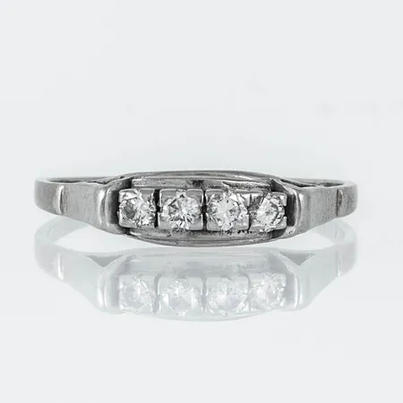Ring i 18K vitguld med 4 x ca 0,07ct briljantslipade diamanter. Den är i storlek 19½, är 1,3 - 5 mm bred och väger 2,6g. Stämplad 18K.