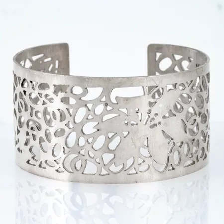 Armring i silver (925/1000). Genombrutet mönster med blommor. Innermått 65 x 58 mm, omkrets 19,5 cm, öppning 28 mm, bredd 35,8 mm. Vikt: 42,9g. Stämplad LS, 925.