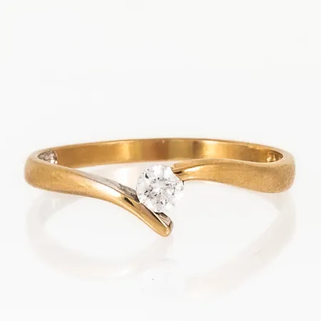 Ring i 18K guld med vit sten. Den är i storlek 19½ , är 2 - 5,7 mm bred och väger 1,9g. Stämplad CCC, 750. Tidigare rhodiumyta bortnött från ena sidan. Naggade facetter på sten men fortfarande fin lyster.