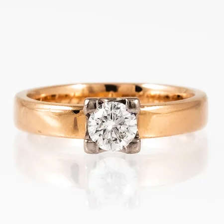 Enstensring i 18K guld med en briljantslipad diamant 0,47ct ca.W/P1, fyrklofattning i vitguld. Den är i storlek 17, är 3,4 - 5,6 mm bred och väger 5,0g. Stämplad GIU (Guldsmedjan i Umeå AB), Stenstorlek 0,47, 18K & Kattfot. Gravyr.