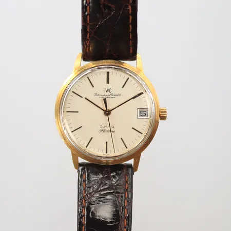Herrur IWC Schaffhausen Flatline 18K Quartz med datum, Ø 33mm, går ej, sliten boett, glaset trasigt, personlig gravyr baksidan med bl a årtal 1978. kronan utbytt, läderband ej original och trasigt.  #2262312