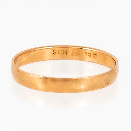 Slät ring i 18K guld, den är i storlek 19½, är 3 mm bred, 0,7 mm hög och väger 1,8g. Stämplad SCH (Schalins Ringar, Östersund), 18K, kattfot.