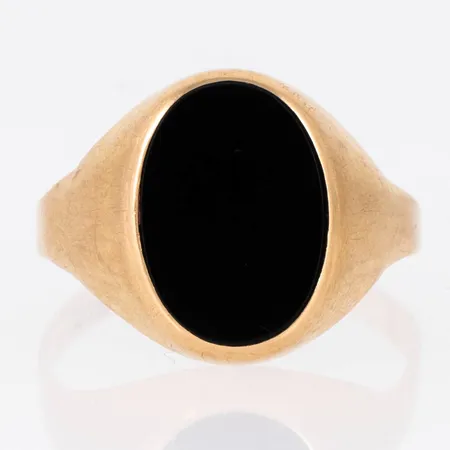 Klackring i 18K guld med svart sten (onyx el. agat). Den är i storlek 19½, är 2 - 15,5 mm bred och väger 3,8g. Stämplad 18K & svensk importstämpel. Ojämn skena. Repig.