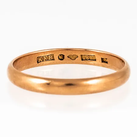 Slät ring i 18K guld. Den är i storlek 22½, är 3,5 mm bred, 1,4 mm hög och väger 4,2g. Stämplad B7 (1904) el. R7 (1919), KEB (Knut Edvard Berg, Umeå) 18K & kattfot. 