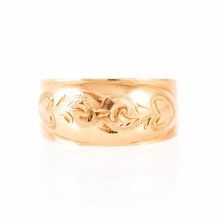 Doserad ring i 18K guld med utvändig mönstergravyr. Den är i storlek 14½, är 3,6 - 7,6 mm bred och väger 1,8g. Gravyr.