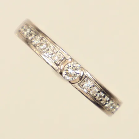 Ring med diamanter ca 14 x 0,01+1 x ca 0,05-0,10ct, stl 16¾, bredd ca 3mm, vitguld, repig, bör rodieras om, gravyr, 18K Vikt: 3 g