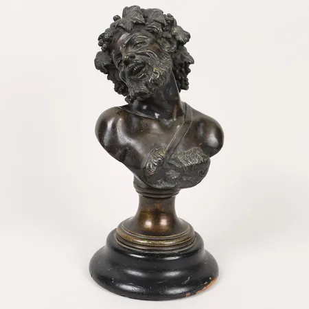 Byst efter Claude Michel Clodion föreställande Bacchus, modellerad med klasar av vinblad och druvor, sockel möjligen senare, bas i bemålat, svärtat trä, åldersbetingat, ställvis hårt slitage. Skickas med postpaket.