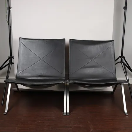 Två Fåtöljer, PK-22 Poul Kjaerholm, formgiven av Fritz Hanszen, svartläder, höjd: 71cm, bredd 63cm, djup 63cm, sitthöjd 35cm, kantskador, mindre reva, bruksslitage.   Specialfrakt, kontakta pantbankskontoret för mer information.