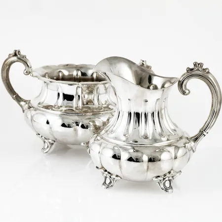 Sockerskål & gräddkanna i silver. Kannan är c:a 11 cm hög. Skålen är c:a 8 cm hög exkl. handtag. Stämplade 830S 854 svenska kontrollstämplar. De väger 375,5g tillsammans. 