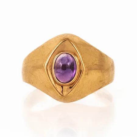 Doserad ring i 18K guld med en oval cabochonslipad ametist ca 4,5 x 6 mm. Den är i storlek 17½, är 3,3 -13,6 mm bred och väger 2,7g. Stämplad K9, GVH, 18K & kattfot. 