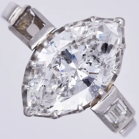 Ring med navettslipad diamant ca 1x2,70ctv, ca W/P1 samt baguetteslipad diamant, stl: 16¾, bredd: ca 2-14mm, 1 diamant saknas, skenan av, Platina 