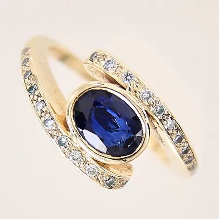Ring med troligen syntetisk safir och diamanter 24 x ca 0,005ct, stl 16¾, bredd 1,8-11mm, slitage på stenar, 18K Vikt: 6,9 g