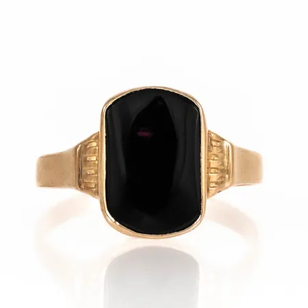 Klackring i 18K guld med svart sten (onyx el. agat). Den är i storlek 21¾ , är 2 - 15,3 mm bred och väger 3,6g. Svaga repor på sten. Ostämplad.