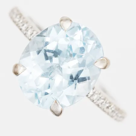 Ring med ovalslipad ljusblå topas, ca 4,94ct, samt briljantslipade diamanter, 28 x ca 0,005ct, totalt ca 0,12ct, kvalitet ca TW(F-G)/VS, stl: 16½, 18K vitguld.   Vikt: 5 g