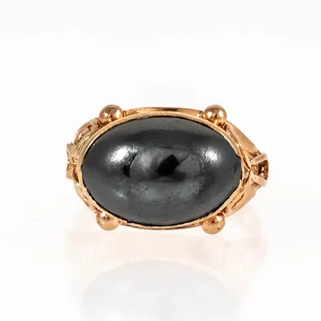 Ring i 18K guld med en cabochonslipad hematit 8,5 x 12,5 mm. Den är i storlek 14½, är 2,2 - 10,3 mm bred och väger 3,6g. 