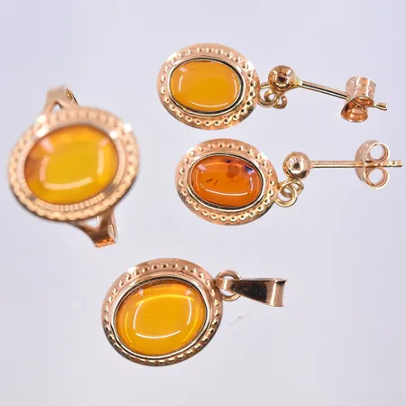 Set- Ring, ett par örhängen och hänge med troligen bärnsten, stl på ring 15½, längd på hänget 20 mm och bredd 11 mm, längd på örhänget 16 mm och bredd 9 mm, 18K. Vikt: 3,7 g