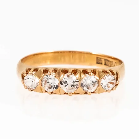 Ring i 18K guld med fem vita stenar. Den är i storlek 19¼, är 2,7 - 5 mm bred och väger 3,5g. Stämplad E9 (1955), K&EC, 18K & kattfot. 