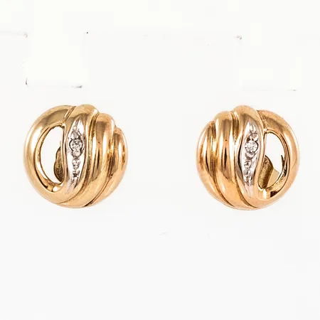 Örhängen i 18K guld med två diamanter á c:a 0,005ct; fattade i vitt guld. De är Ø 9,5 mm och väger 1,7g.