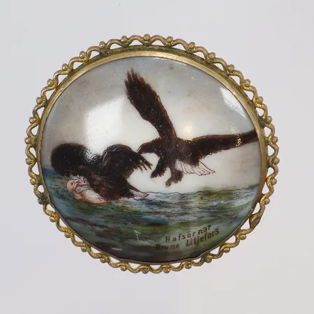 Brosch ram i gulmetall, tryckt porslin med dekor av motiv Efter Bruno Liljefors "Havsörnar", 1900-talets förasta hälft, Ø46mm 