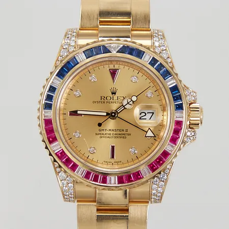 Herrur Rolex GMT-Master II, 18K, automatisk, datum, ref: 116758 SARU, serienummer: M060607, ring med baguetteslipade safirer, rubiner och diamanter, diamanter på hornen, Serti tavla med diamanter och rubiner, tavlan ej original för modellen, oysterlänk 18K, total längd ca 16,5cm, repa i glaset, kopia på värderingsintyg från Nymans Ur 2011, inga tillbehör 
