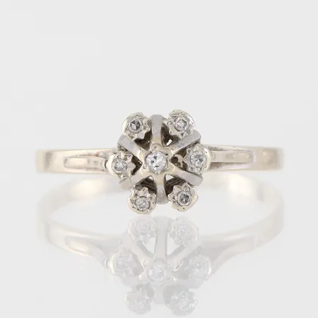 Ring vitguld med 7 st diamanter på totalt 0.09 ct enligt inskription, storlek 19 ½ mm, bredd 1.8-8.4 mm, ej stämplad, 18k. Vikt: 2,5 g