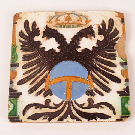 Kakelplatta, tvehövdad örn under kunglig krona, bär datum 1780, ca 19x19, slitage, avslag. 