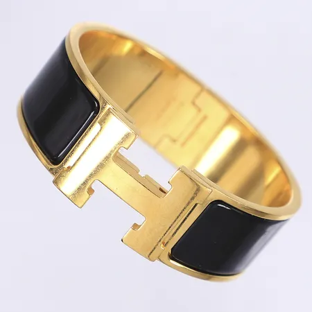 Armband, Hermès Clic Clac, guldfärgad metall med svart emalj, ca 55x45mm, märkt Hermès Made in France, ST0126, bredd: 20mm, box, kvitto från Hermes Munchen 2022, repig, påtagligt slitage, låser ej helt korrekt