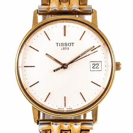 Herrur Tissot 1853 i 18K guld. Boett Ø33,5 mm, datum, quartz, metallband (slitet). Går ej - batteribyte krävs? Gravyr. Repigt glas. Bruttovikt 66,3g. 