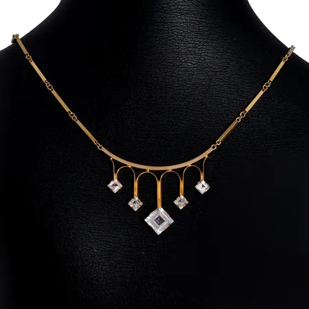 Collier, 18K guld, integrerat hänge med Bergkristaller 4x4 - 8x8 mm, otydlig tillverkarstämpel, 1967, svensk kontrollstämpel, längd 41 cm, bredd 1,3 - 26 mm, fint skick, yttersta stenen med kantavslag, övriga stenar utan anmärkning Vikt: 8,8 g