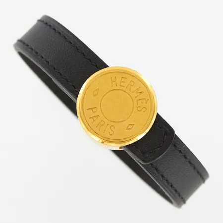 Armband Hermés, Clou de Selle, gulmetall med två läderremmar i svart och orange, ca 16,5-18cm, spännet ca Ø20mm, bruksrepor, med original etui och påse. 