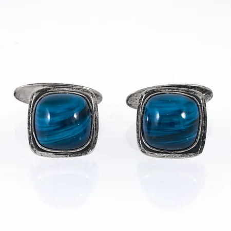 Manschettknappar i silver med blå slaggsten. Motiven är 14,5 x 14,5 mm. De väger 14,0g. Stämplade VJ (Victor Janson Lindesberg), O9 (1964) & kattfot.