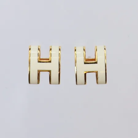 Ett par örhängen Hermes, Mini Pop H earrings, ref-nr: H608002F, guldfärgad metall med vit emalj, fläckig dustbag, kvittokopia från Hermés Hamngatan 2023, box med slitage. 