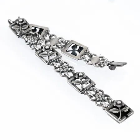 Armband i silver med blomdekor. Det är 19 cm långt, 10 - 12 mm brett och väger 20,4g. Kistlås. Stämplad Z8 (1950), GD&Co (Guldvaruaktiebolaget G. Dahlgren & Co AB, Malmö), silver & kattfot.  