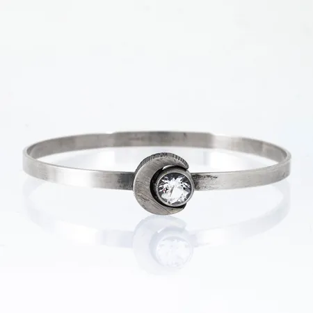 Armring i silver (925/1000) med bergkristall, Karl Laine, Finnfeelings Finland. Innermått ca 16,5 cm, 55,5 x 50,5 mm. Bredd 3,7 - 12,5 mm. Vikt: 8,2g. 