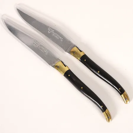 Ett par knivar, för kött, Laguiole en Aubrac, mässingsdetaljer samt grepplattor av trä, total längd 23,5cm, bladets längd 11cm, buksslitage, svaga repor.  