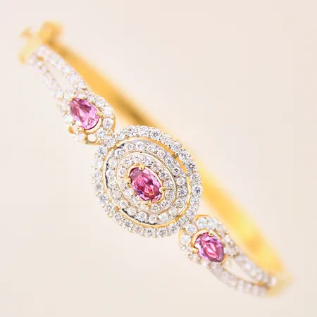 Armband med vita och rosa stenar, stelt, öppningsbart, 60x53mm, bredd 5-17mm, två stenar saknas, 18K Vikt: 17,2 g