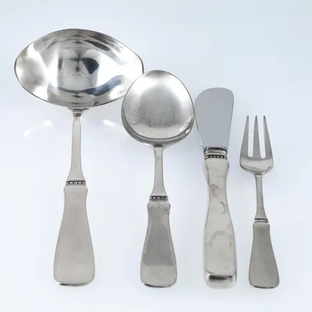 12 efterrättsskedar längd 155 mm, 2 smörknivar längd 165 mm, 4 smågafflar längd 124 mm, 1 såssked längd 170 mm. Silver (830/1000), modell Uppsala, MGAB. Fint skick. Vikt skedar, gafflar och såssked: 507,9g. Bruttovikt knivar med rostfritt blad: 106,3g. 