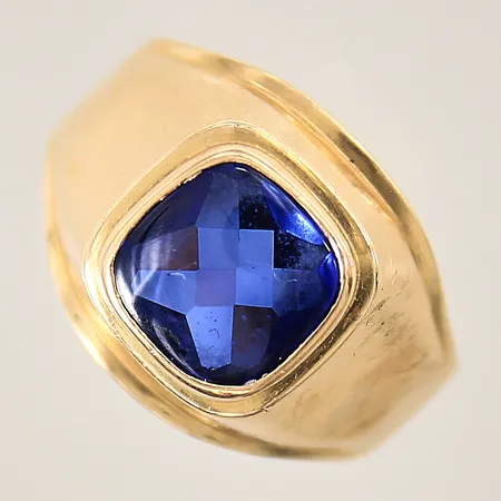 Klackring med syntetisk safir, stl 20¼, bredd 4-16mm, skena med repor, hack samt bucklor, 18K  Vikt: 5,1 g