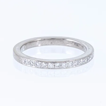 Alliansring i 18K vitguld med 13 x 0,01ct briljantslipade diamanter. Den är i storlek 15¾, är 2 mm bred, 1,9 mm hög och väger 2,8g. Stämplad SCH (Schalins Ringar, Östersund), 18K & kattfot. Stenstorlek 0,13ct ingraverat. 