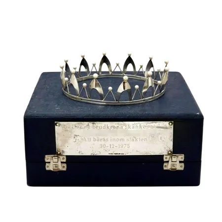 Exklusiv Brudkrona - Arvo Saarela Enköping 1962, silver, odlade sötvattenspärlor Ø4,5-5,0 mm, blåvitrosa med god lyster, stämplad med både tillverkarstämpel AMS och Saarela i skrivstil, märkt HANDARBETE, diameter Ø11 cm, höjd 30 mm, svaga namngravyrer liksom årtal förekommer, fint använt skick, originaletui med slitage medföljer (18x18x8 cm), plakett i silver på framsidan, gravyr Vikt: 40,2 g