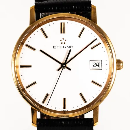Herrur Eterna i 18K guld med svart läderband. Boett Ø 33,5 mm, datum, safirglas, quartz, gravyr. Bruttovikt: 26,5g. Går ej, batteribyte krävs?