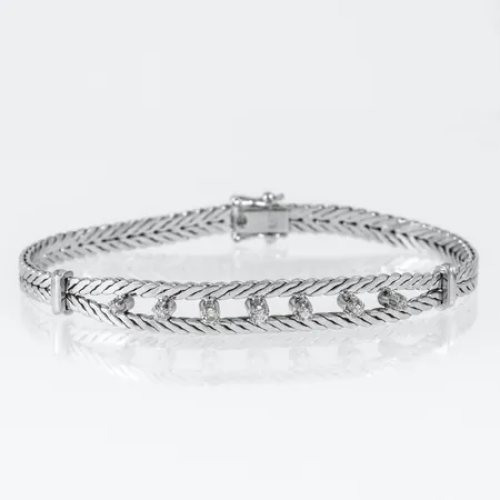 Armband i vitt guld 18K med diamanter 2 x c:a 0,015ct, 2 x c:a 0,02ct, 2 x c:a 0,025ct & 1 x c:a 0,03ct. Det är 18,5 cm långt, 4,6 - 7,8 mm brett och väger 17,6g. Kistlås. 