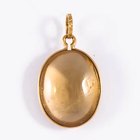 Hänge i 18K guld med en orangegul sten. Inneslutning som når ytan på ena sidan. Det är 27 mm långt inkl. ögla och väger 2,9g. Tillverkat 1963 av Kjellins i Umeå.